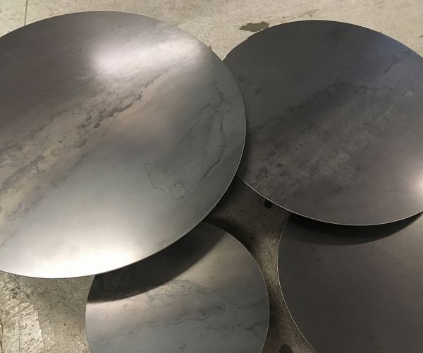 Table basse ronde en acier finition de surface brute et vernis de protection. 